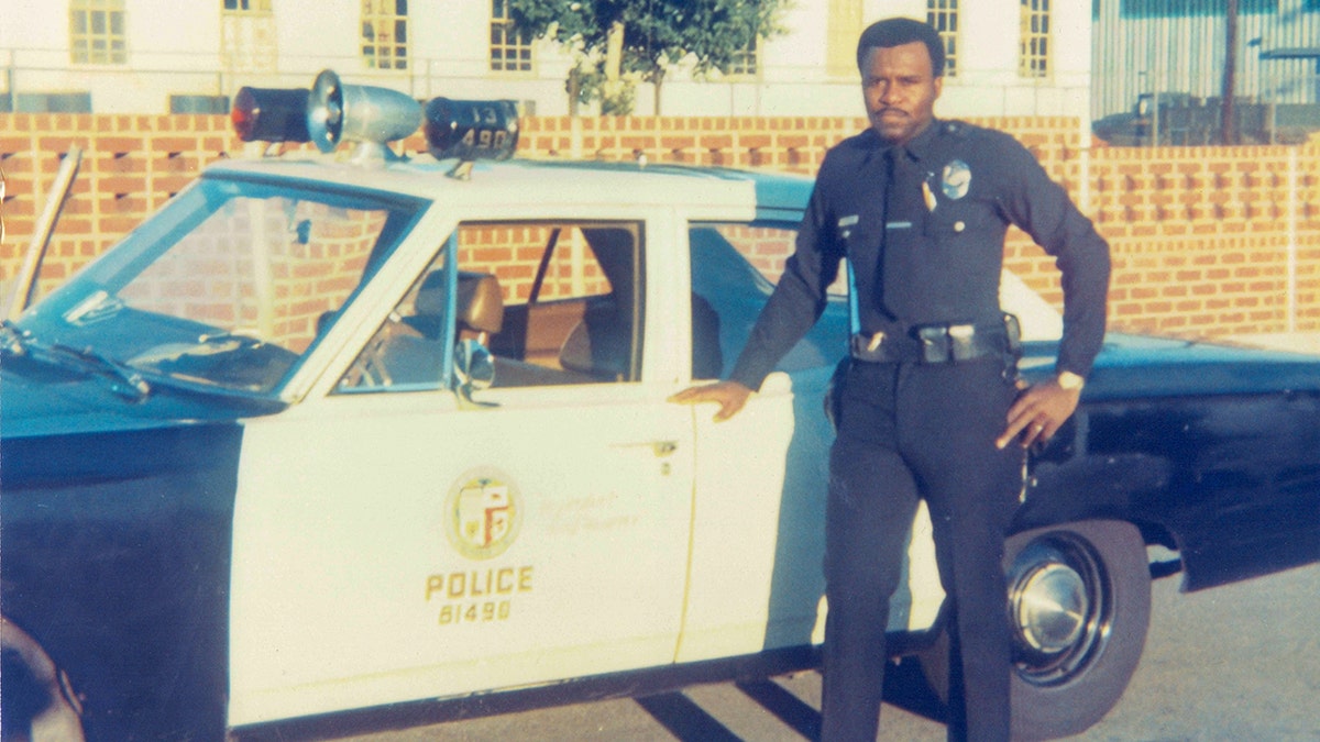 A policeman in front of a car.