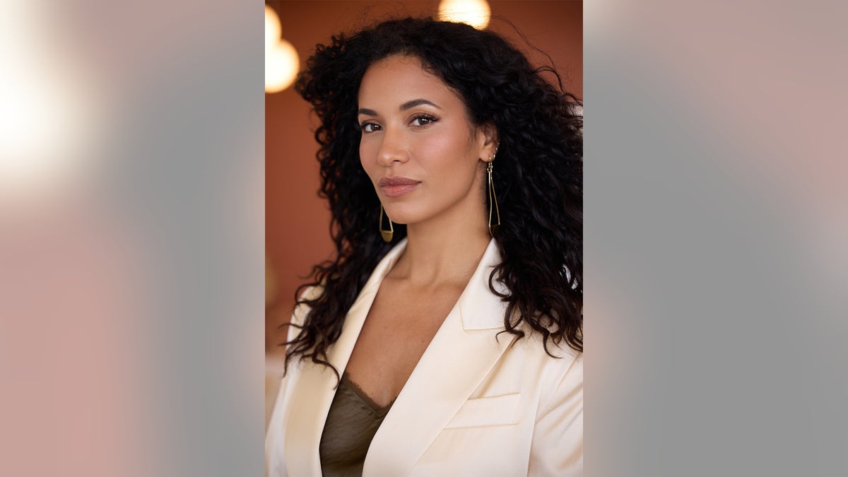 A close-up of Lisa Phillips wearing a white blazer and a satin blouse.