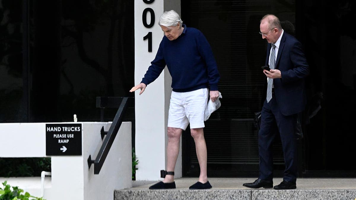 An ankle monitor fitted to the leg of former Abercrombie and Fitch CEO Mike Jeffries is visible as he walks away from an office building.