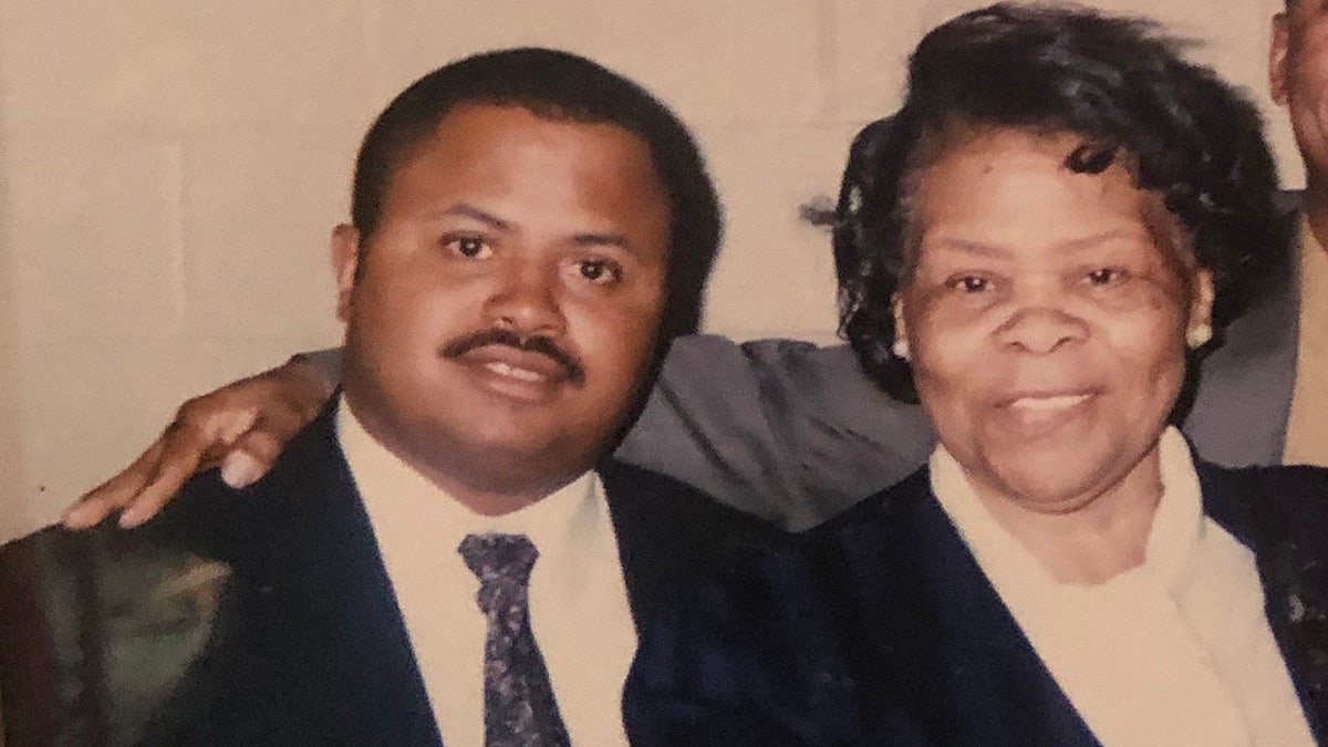 Michael Beverly in a suit sitting next to his mother.