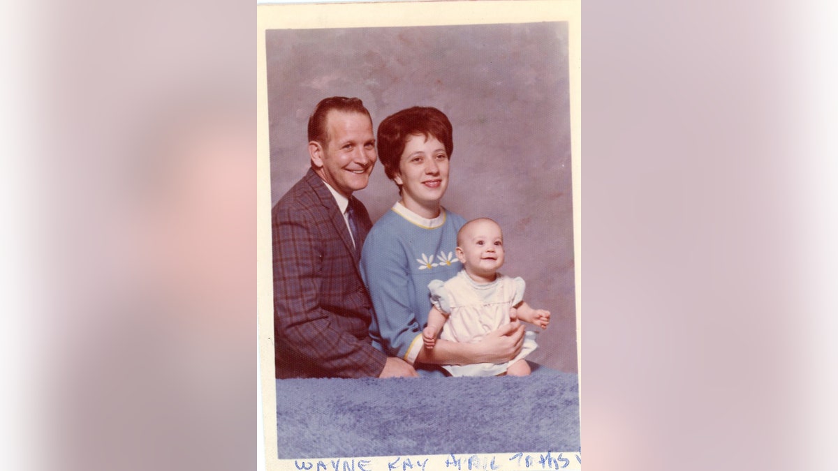 Edward Wayne Edwards posing in a family portrait with his wife and April.