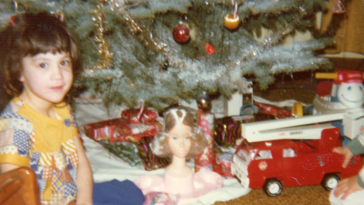 April Balascio surrounded by toys under a Christmas tree.