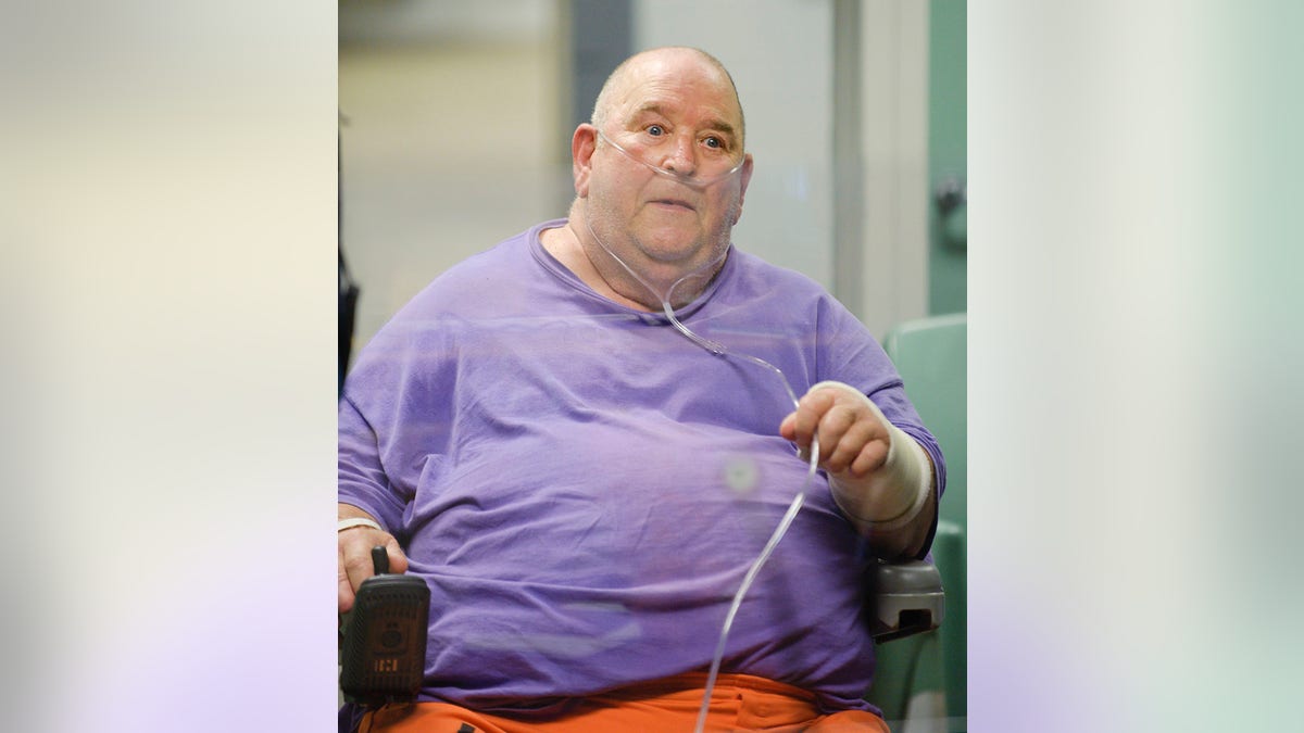 A close-up of Edward Wayne Edwards in a purple shirt with a breathing tube.