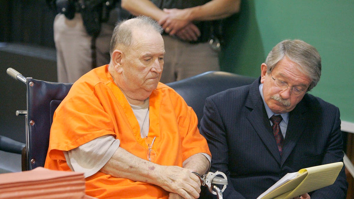 Edward Wayne Edwards in an orange jumpsuit sitting next to his attorney.