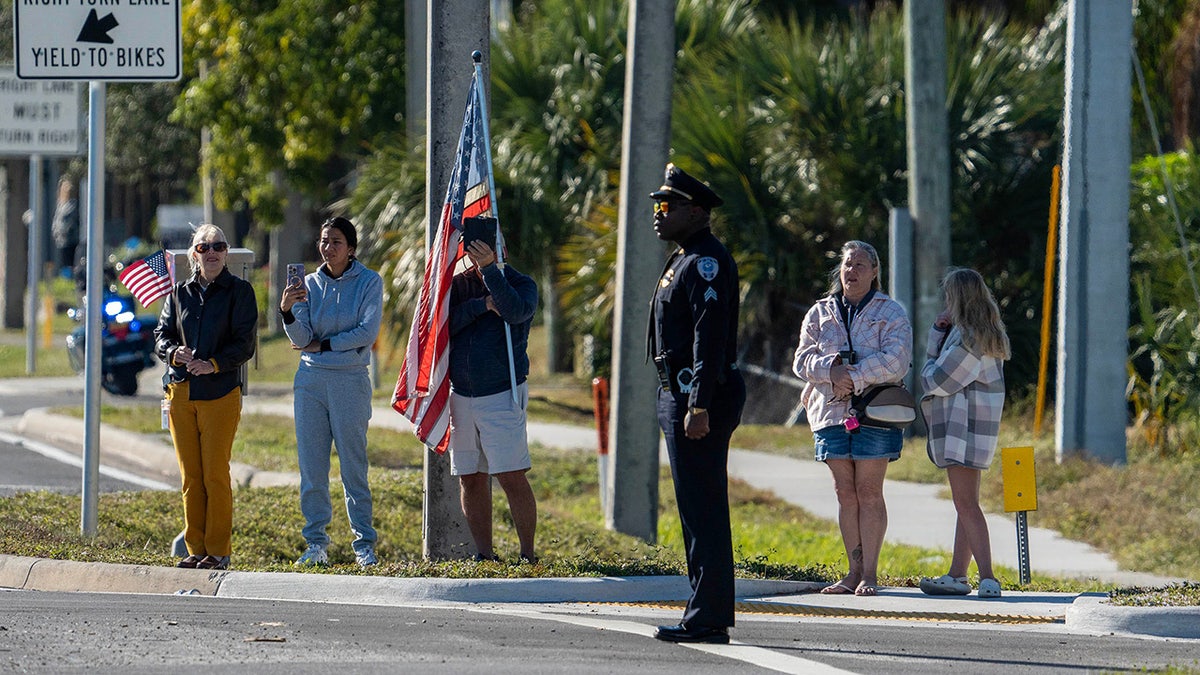 People watch along State Road 7 as a procession passes by for three Palm Beach County Sheriff's Office deputies who died last month