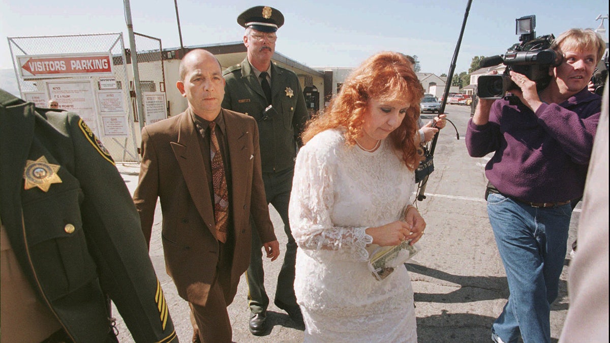 Doreen Lioy, center, of San Rafael, Calif., walks with her head bowed as she and author Phillip Carlo, left, are escorted by prison guards