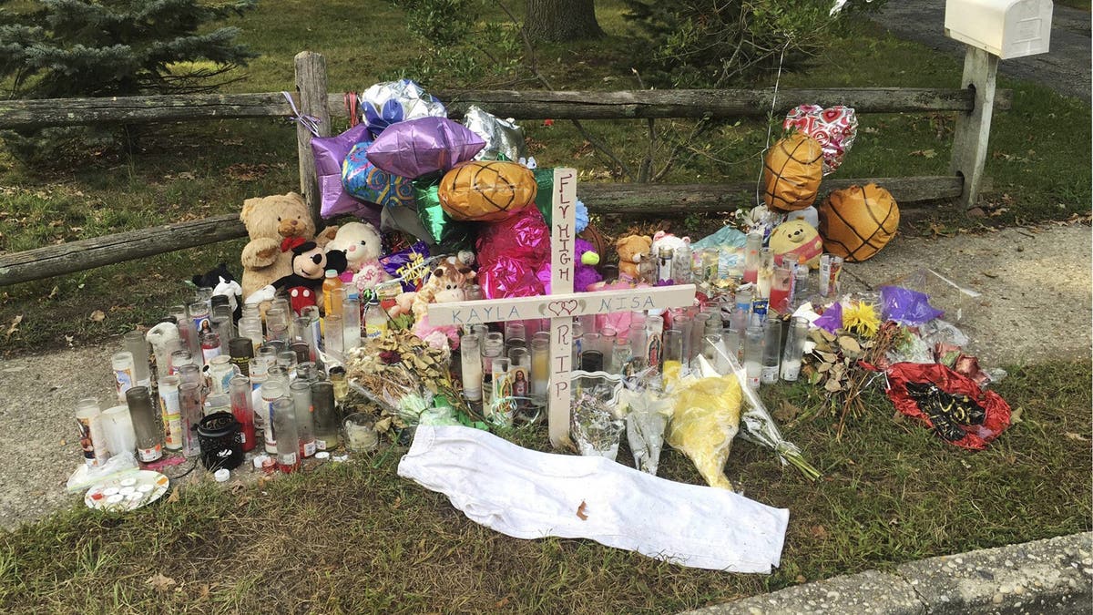 Candles, flowers, balloons and a cross arranged in a sidewalk in memory of MS-13 murder victims Nisa Mickens and Kayla Cuevas