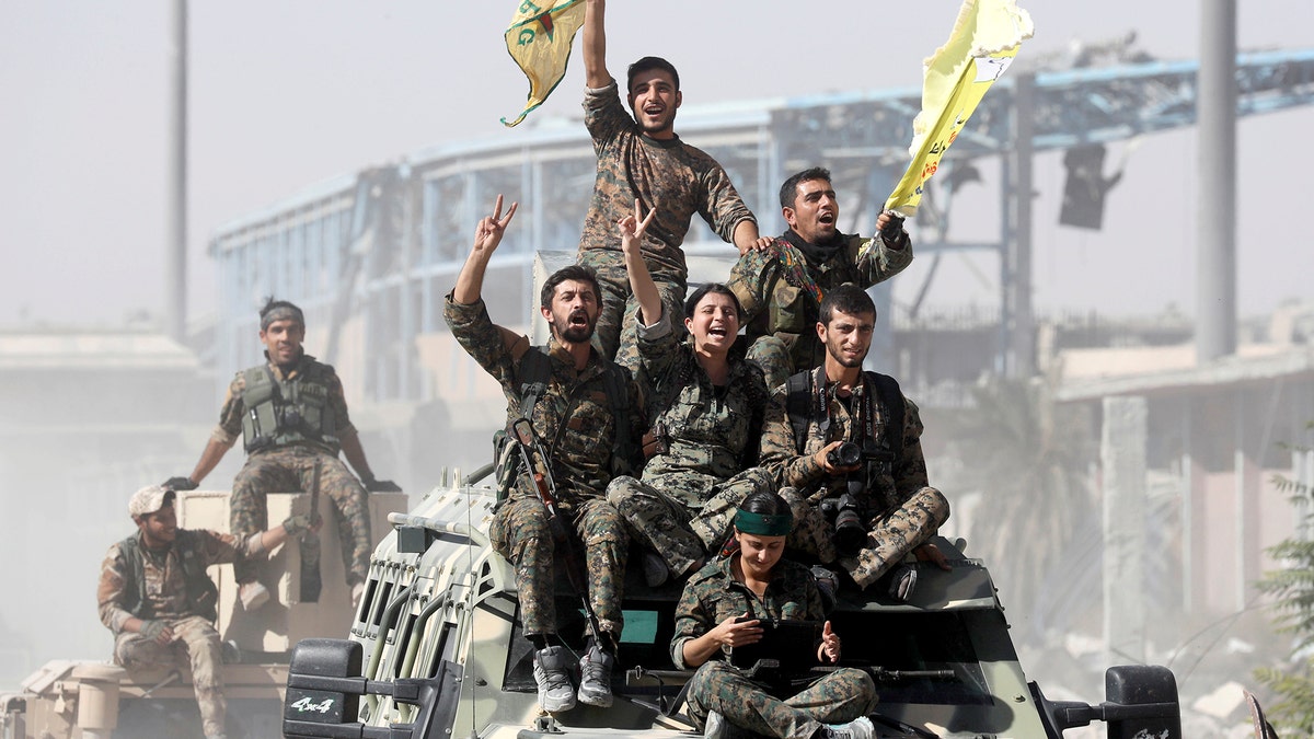 Syrian Democratic Forces (SDF) fighters ride atop military vehicles as they celebrate victory in Raqqa, Syria, October 17, 2017. REUTERS/Erik De Castro TPX IMAGES OF THE DAY - RC18150D4560