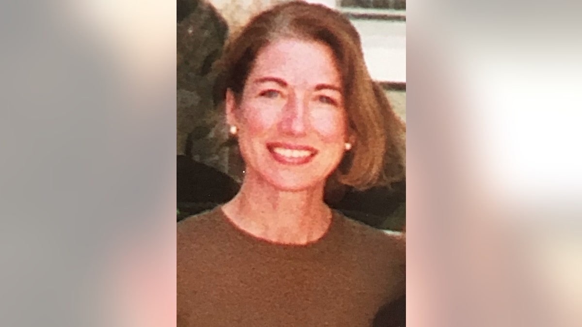 Leslie Preer wearing a brown sweater and pearl earrings.