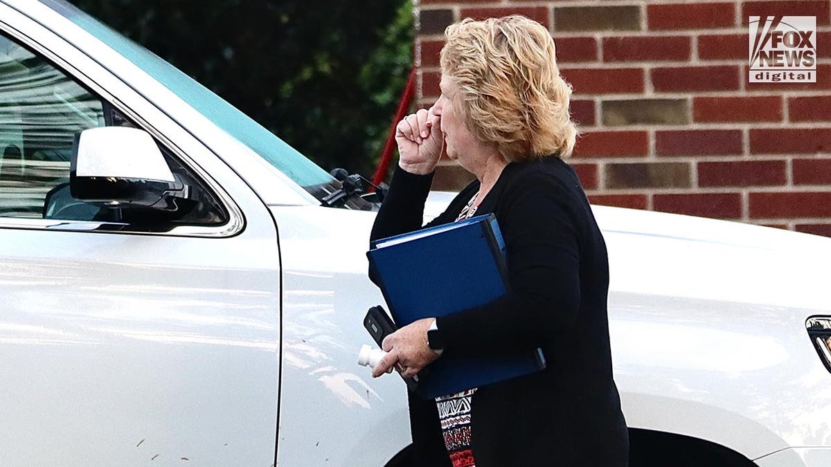 Becky Hill carries a folder, her phone as she heads towards a white truck