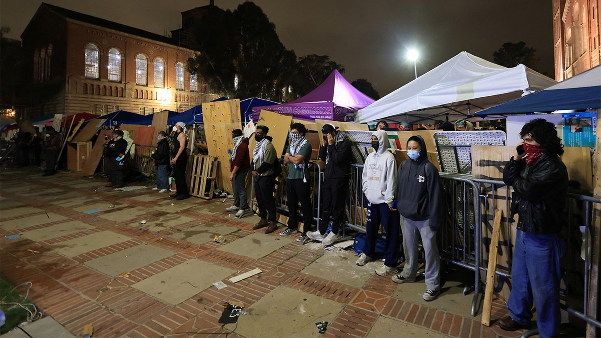 UCLA protesters form a human wall with tents and cardboard during protests