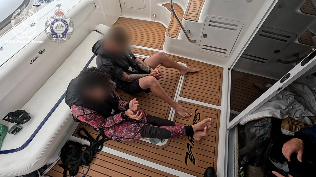 two men in custody sitting aboard boat