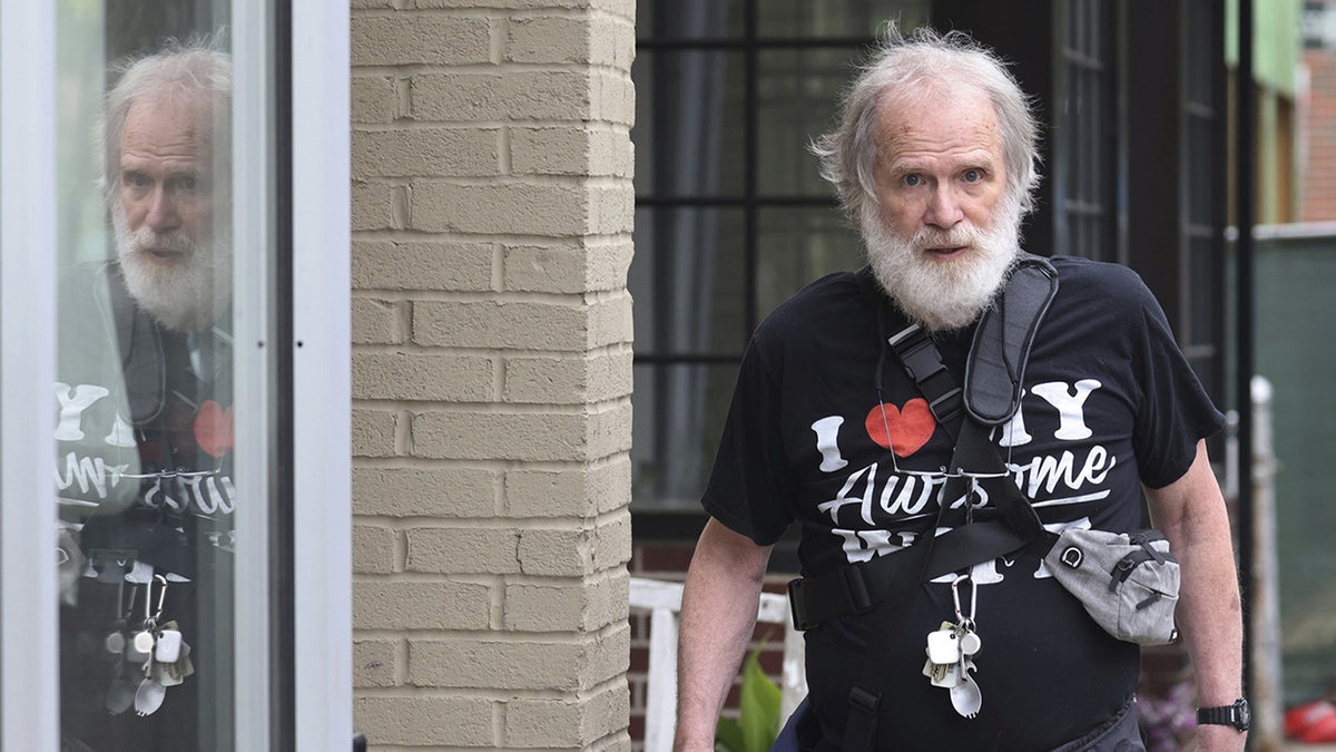 James Lewis wearing a black and printed shirt walking outside.