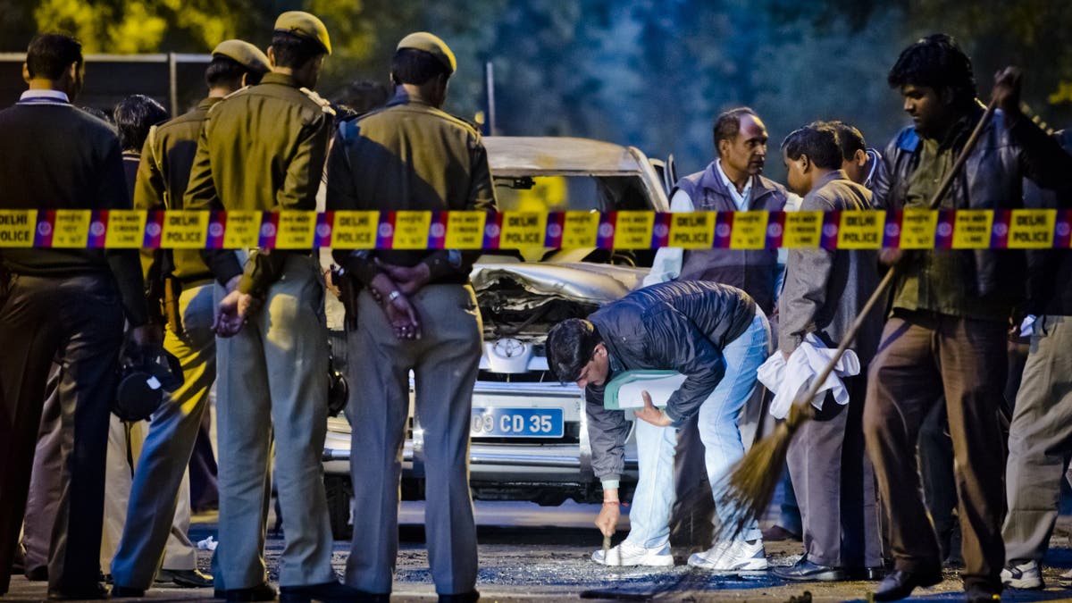 Police and forensic officers examine a damaged Israeli embassy vehicle after an explosion, on February 13, 2012, in New Delhi, India.