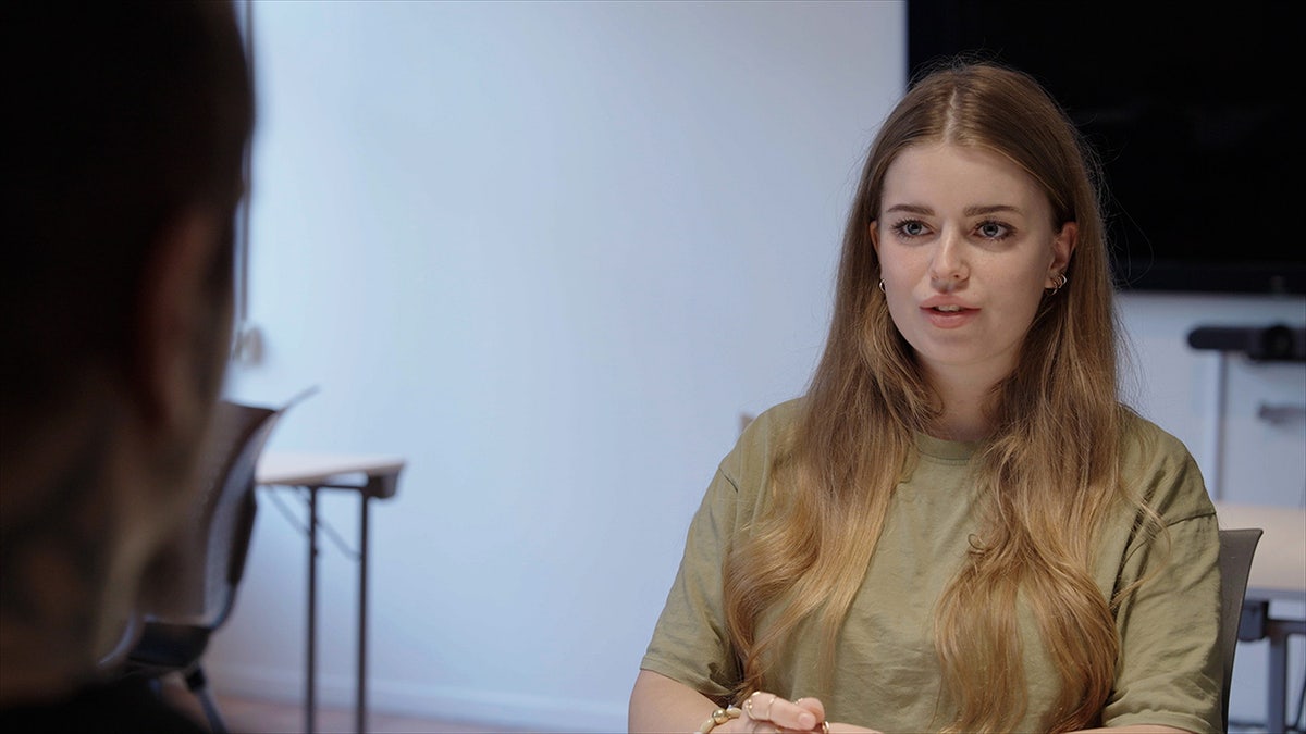 Jamie-Lee Arrow wearing an olive shirt speaking to her father.