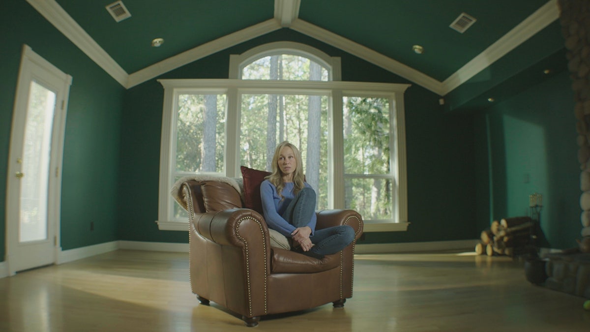Sherri Papini sitting on a brown couch inside a green house.