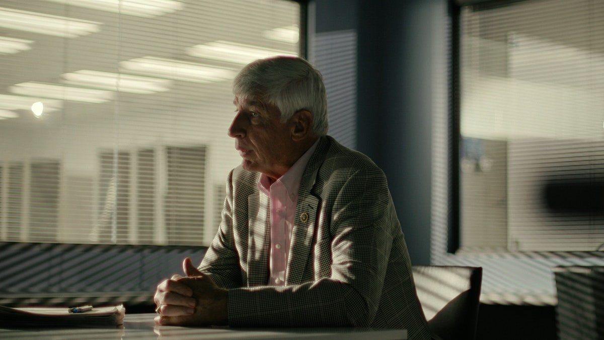 An investigator inside an office looking away.