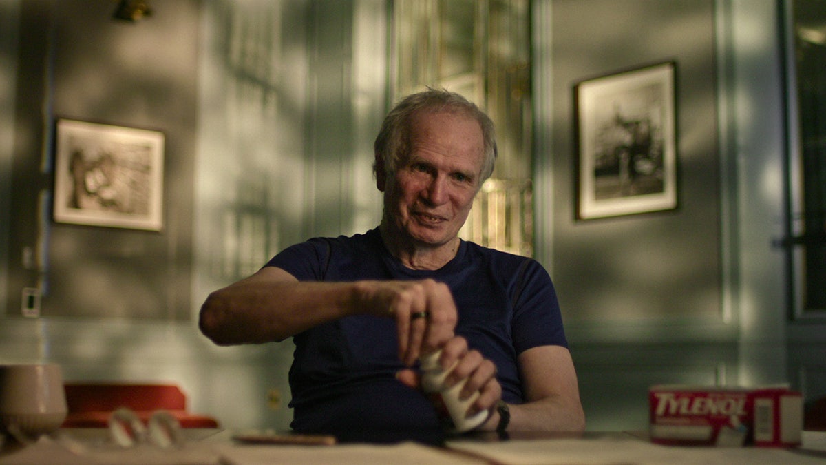 James Lewis wearing a black shirt trying to open a bottle of Tylenol.