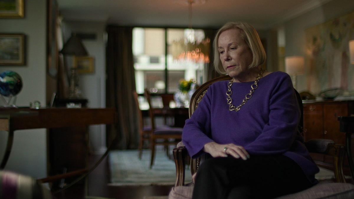 Jean Regula Leavengood wearing a purple sweater and looking down.