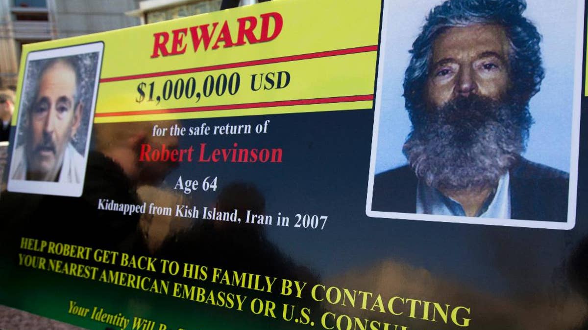 FILE -- In this March 6, 2012 file photo, an FBI poster showing a composite image of former FBI agent Robert Levinson, right, of how he would look like now after five years in captivity, and an image, left, taken from the video, released by his kidnappers, in Washington during a news conference. The family of Levinson, who went missing in Iran a decade ago on an unauthorized CIA assignment, filed a lawsuit Tuesday, March 21, 2017, against Iran. The lawsuit in U.S. federal court describes in detail offers by Iran to 