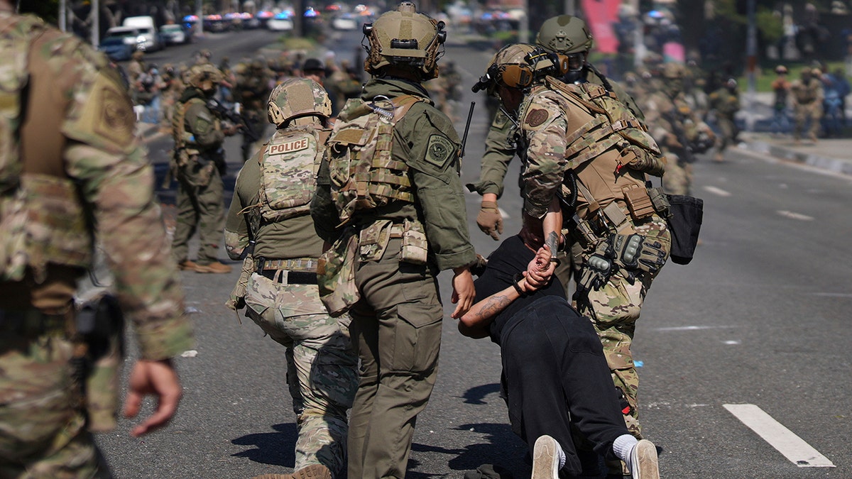 police in green camo in streets of LA