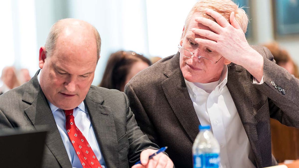 Alex Murdaugh holds his head up to his forehead as his attorney looks at notes