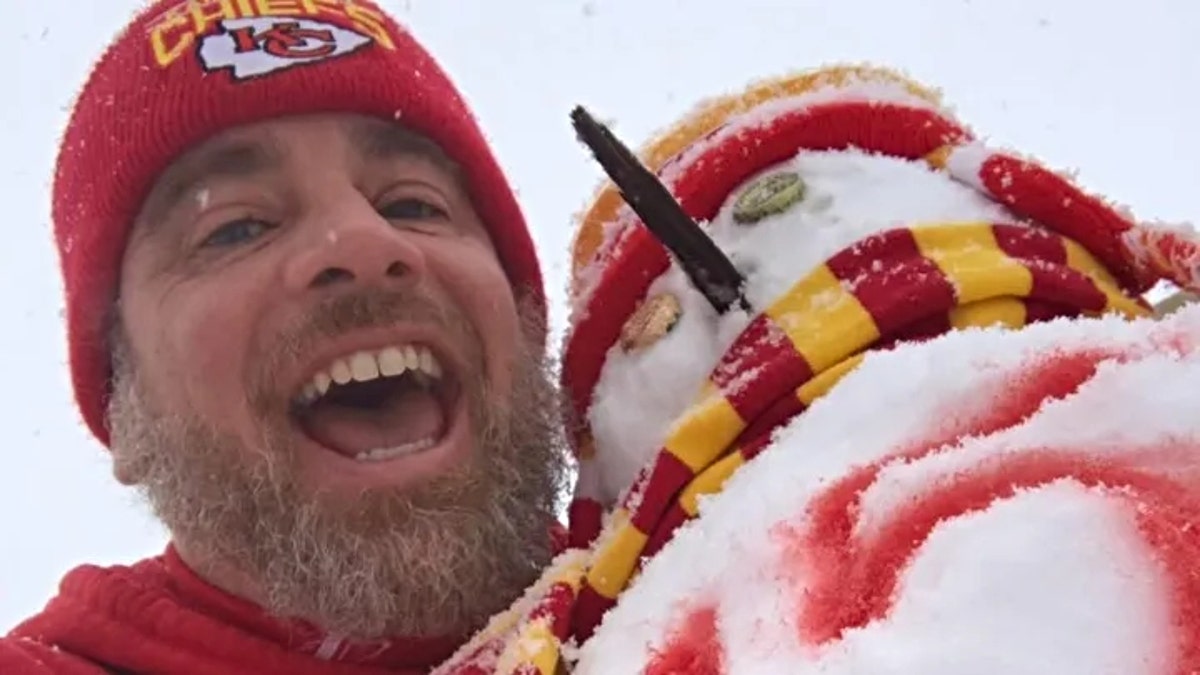 Dennis Sharkey Jr. poses next to a snowman wearing Kansas City Chiefs gear