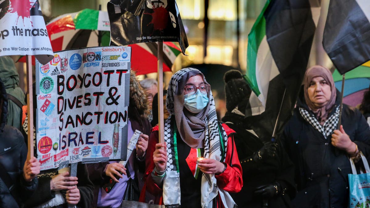 Protesters hold candles and placards in support of Palestine during the emergency vigil.