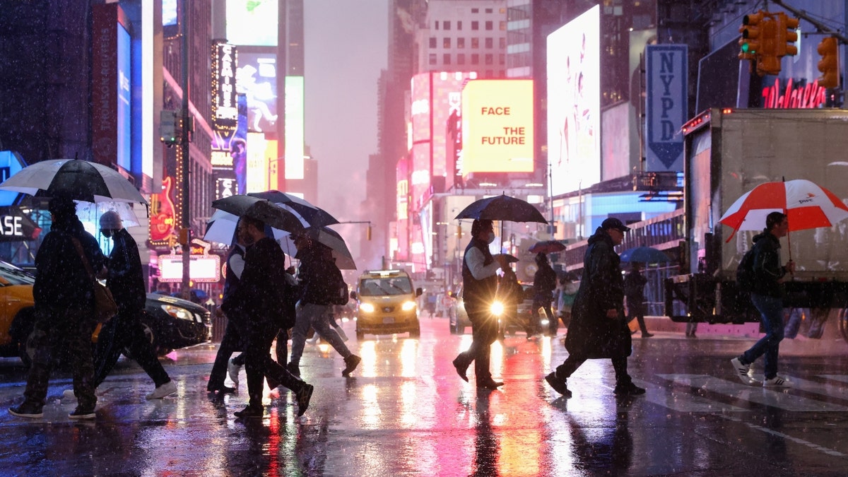 people crossing street at night while it rains