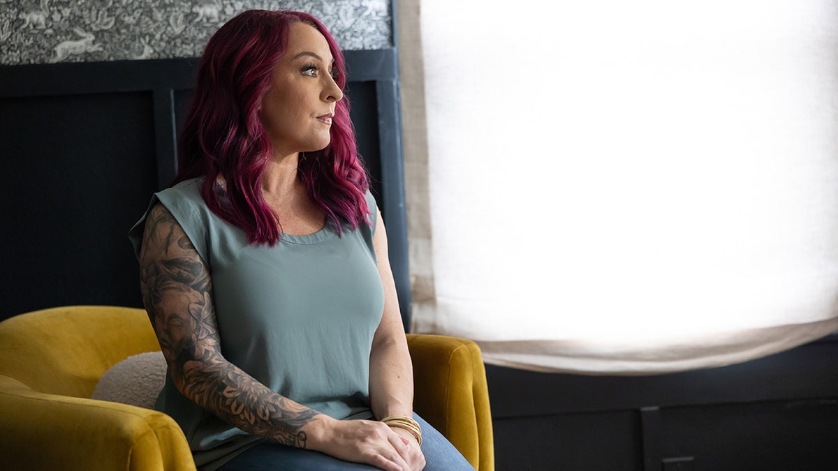 Bekah Charleston wearing a grey shirt sitting in front of a light looking away.