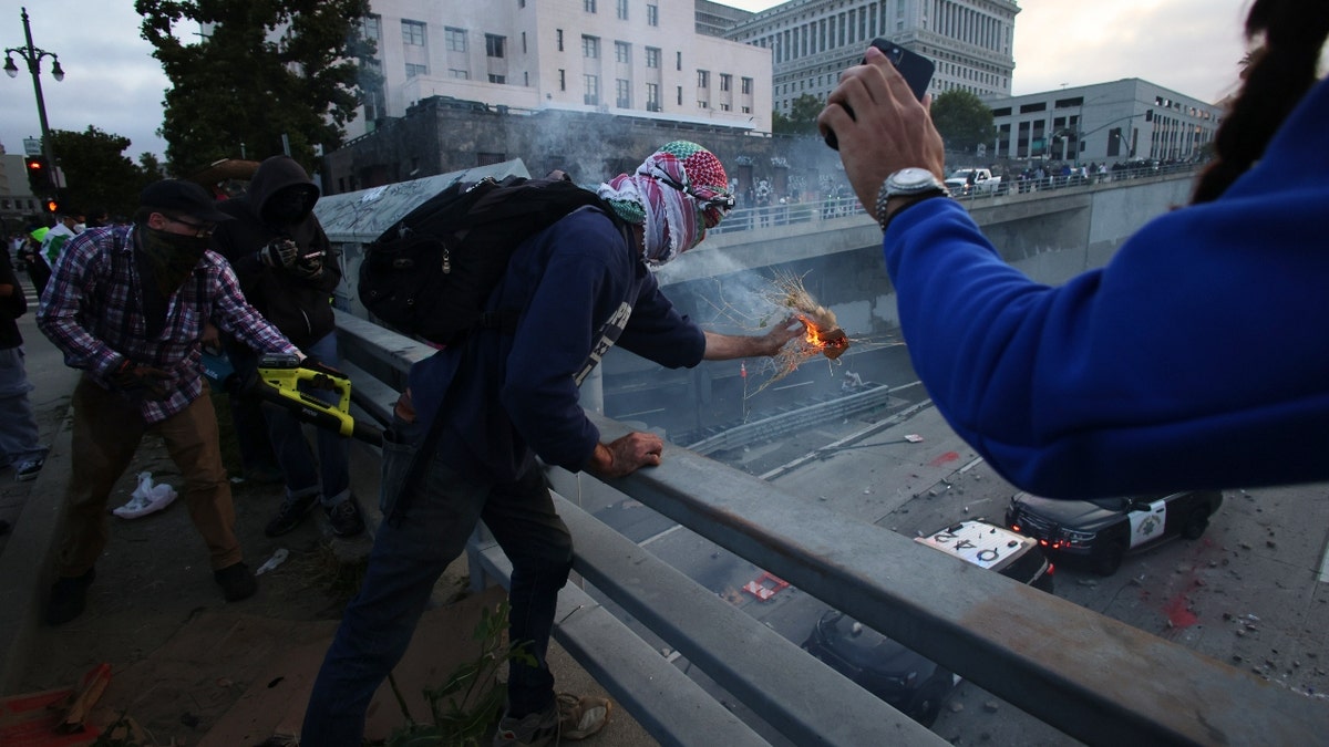 Protesters throw objects to the police vehicles on a Freeway near the Metropolitan Detention Center in downtown Los Angeles, Sunday, June 8, 2025.