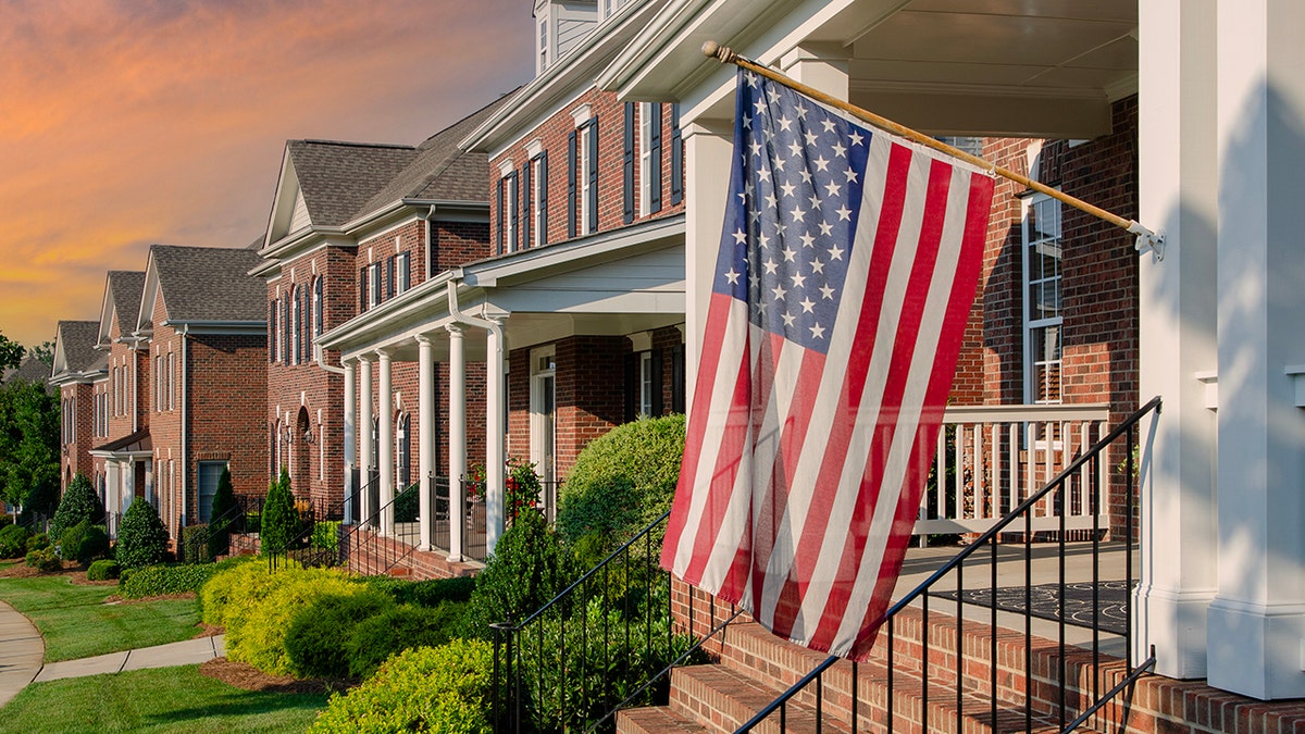 American Flags hang from the front of this traditional, brick homes in an All-American neighborhood. For Flag Day use