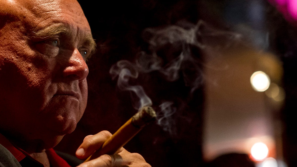 A side profile of Dennis Hof smoking a cigar.