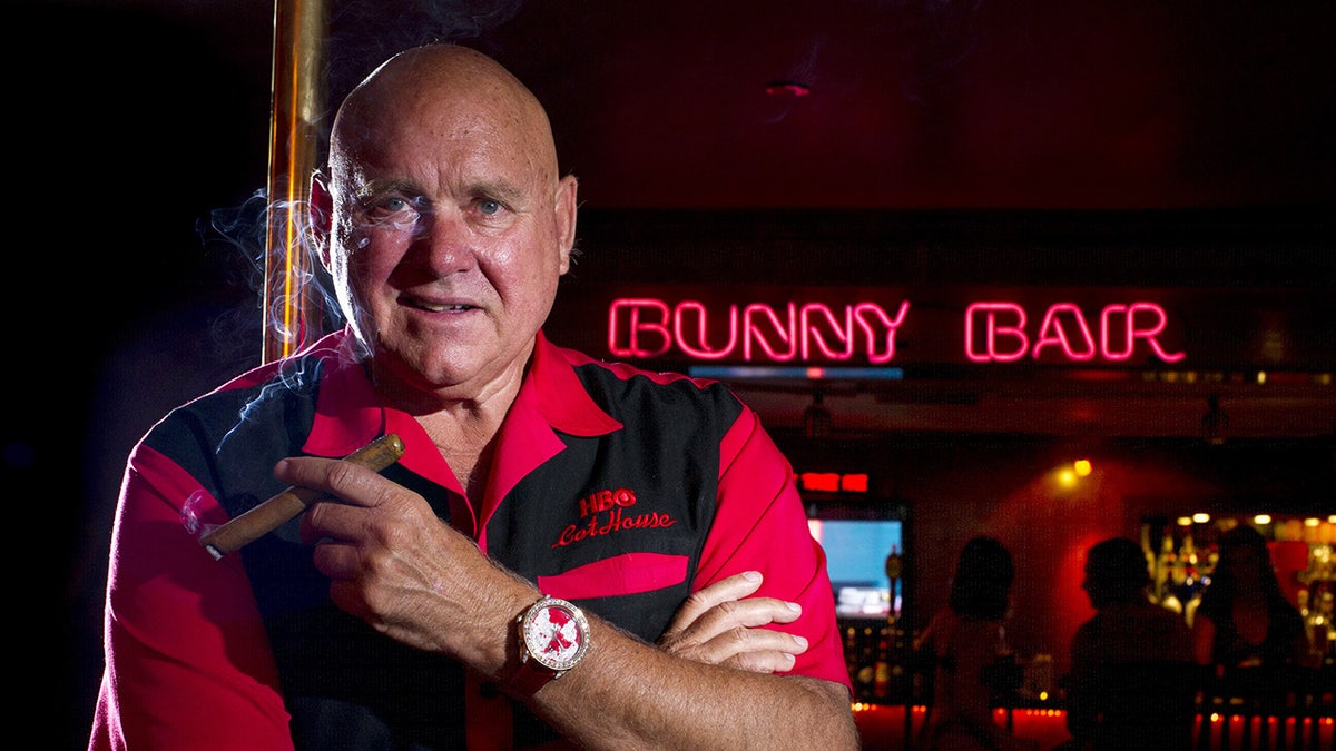 Dennis Hoff wearing a black and red shirt holding a cigar.