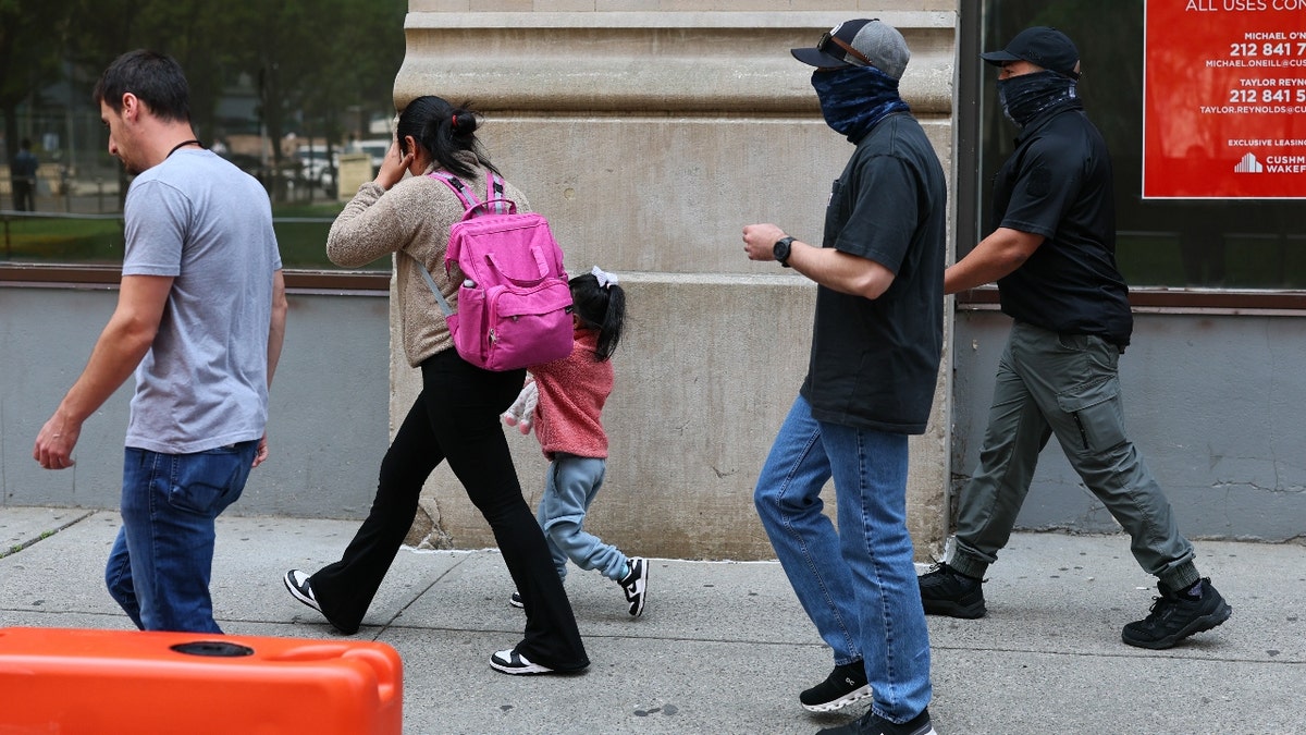 A woman and child are escorted by federal agents after exiting an Intensive Supervision Appearance Program office on June 04, 2025 in New York City.
