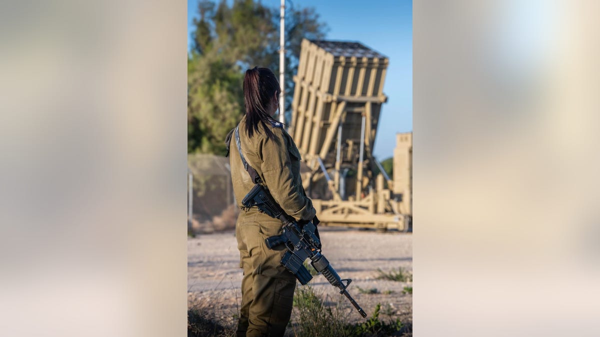 A female soldier stands by an Iron Dome battery. Women make up half of all the Iron Dome operators and extend their service by a year to three years.