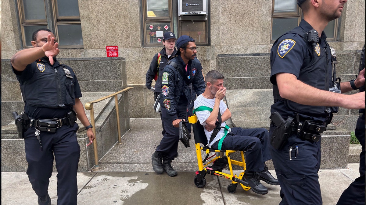 officers escort a man in a gurney outside a New York county courthouse