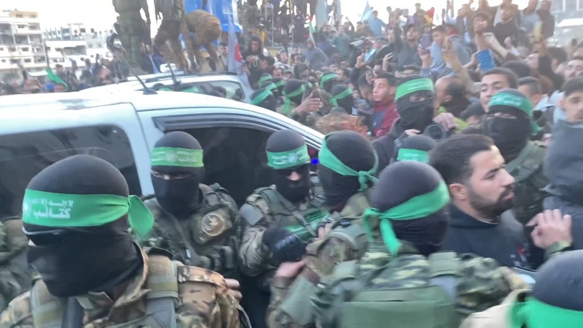 Hamas terrorists emerge in a show of strength, escorting Red Cross vehicles carrying three Israeli hostages to be released as part of the ceasefire deal.