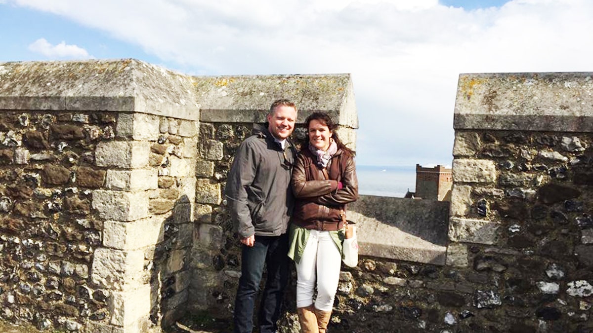 Angela and James Craig pose for photo with brick wall in background