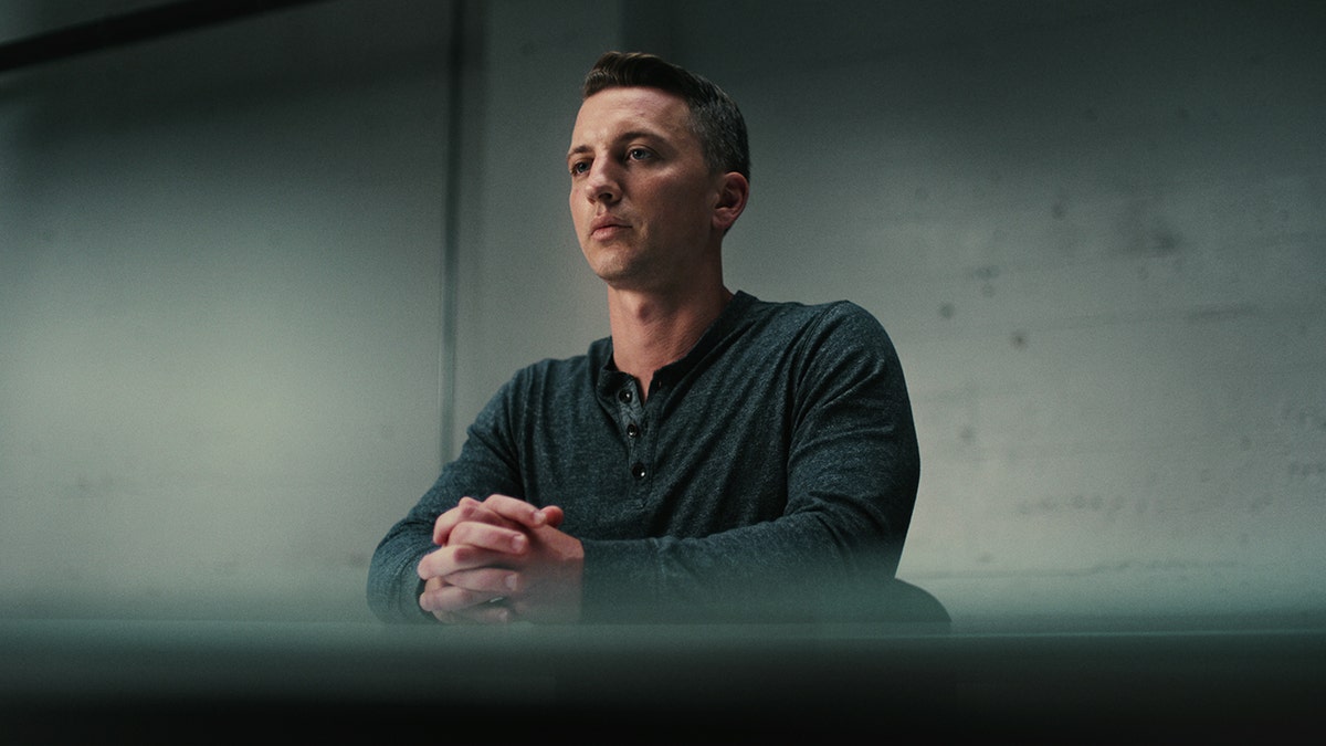 Aaron Quinn sitting in a interrogation room.