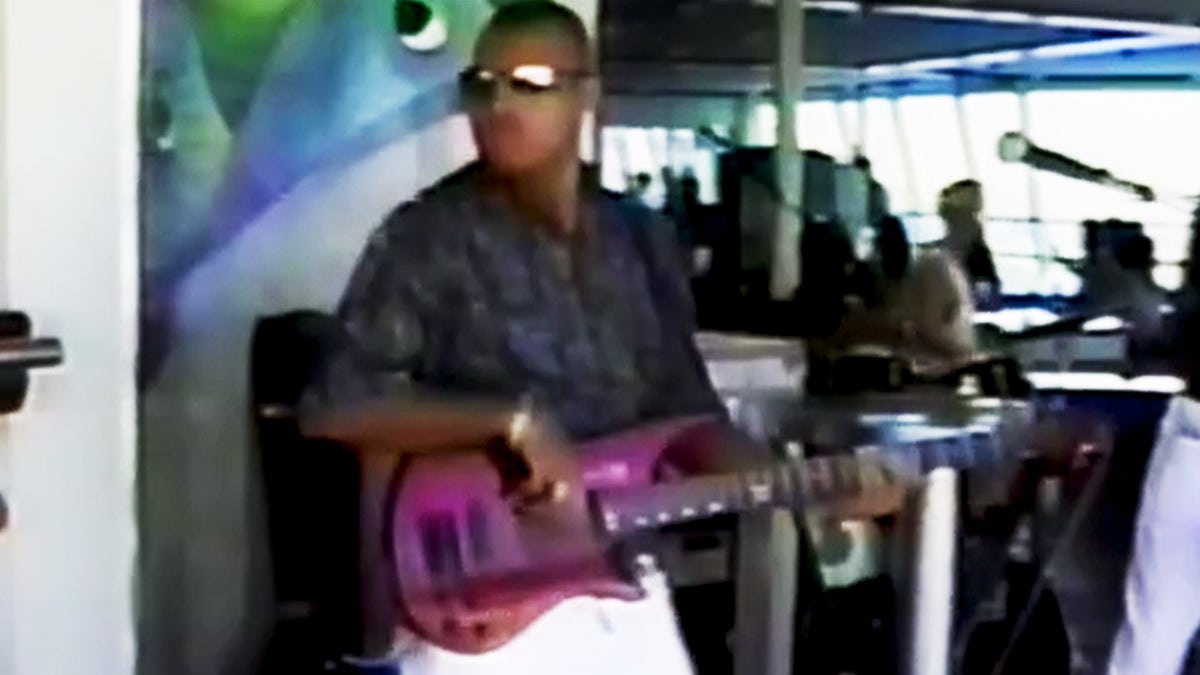 Alastair Douglas wearing a dark shirt and playing a purple guitar.