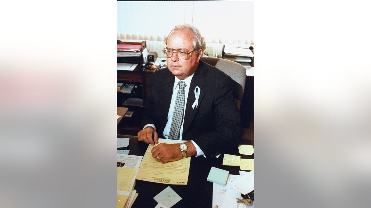 John Shine wearing a suit and a white ribbon.