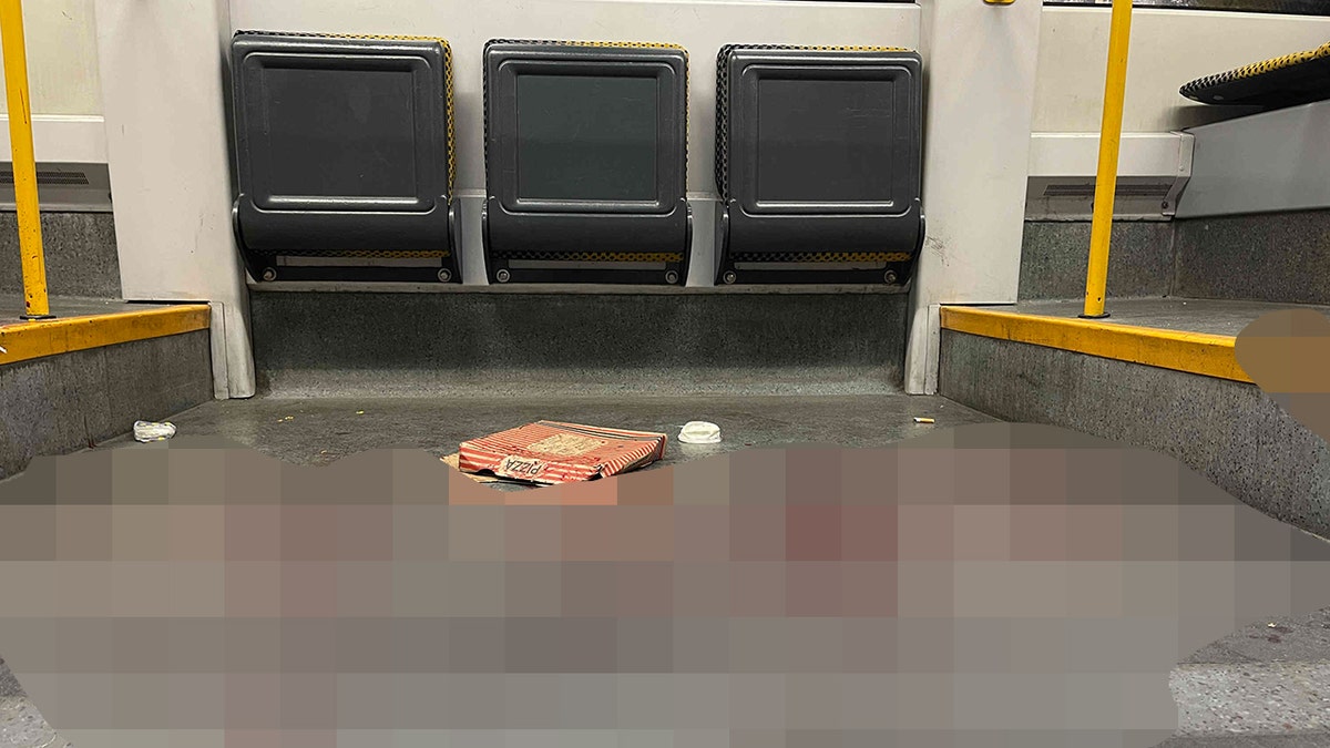 A pizza box on the floor of a German tram next to a pool of blood.