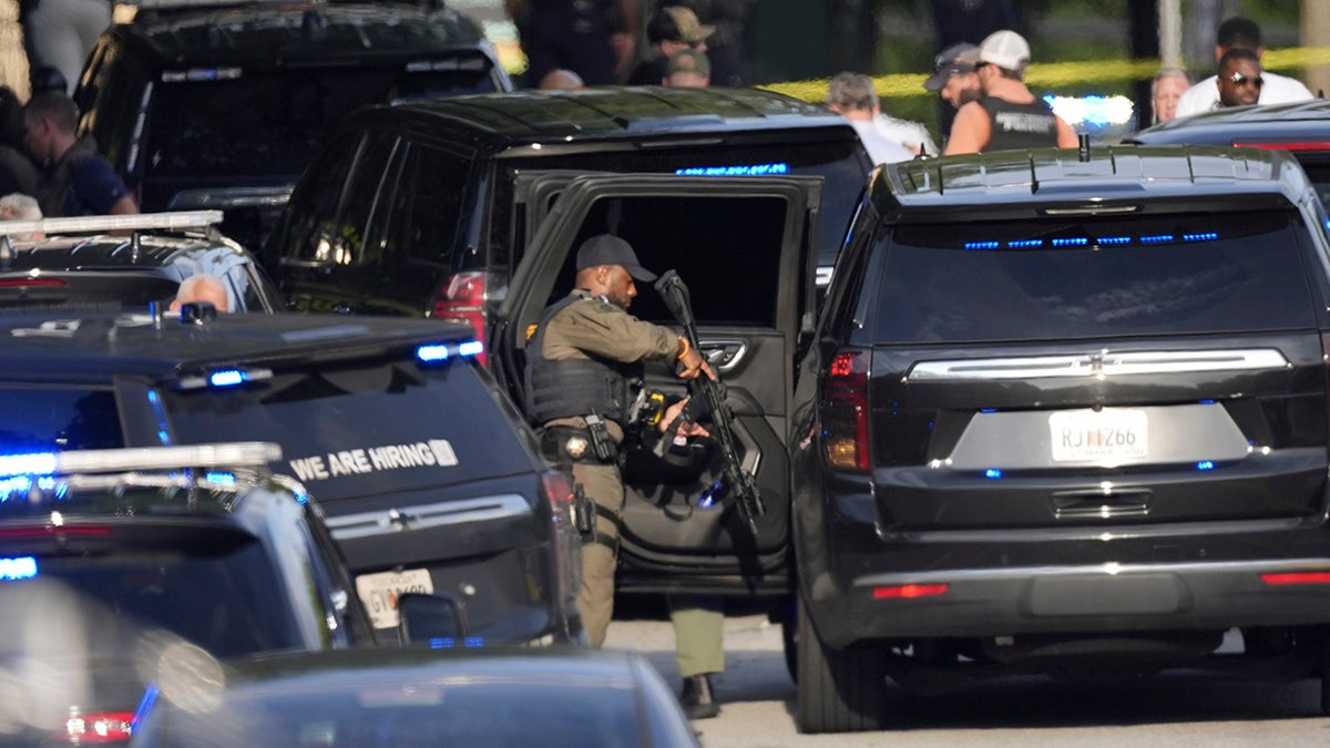 An armed Police officer prepares near the scene of a shooting