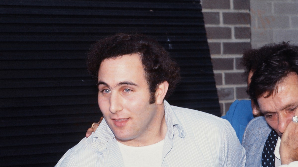 David Berkowitz in a white shirt smirking after his arrest.