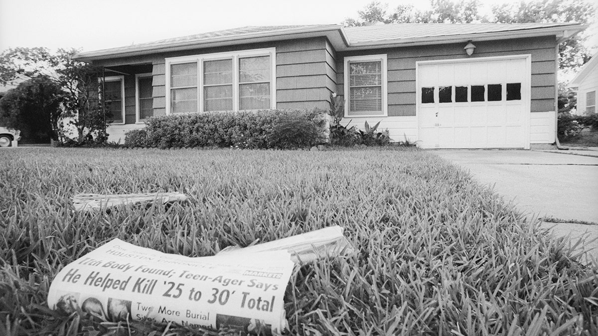 A house with a newspaper on the lawn.