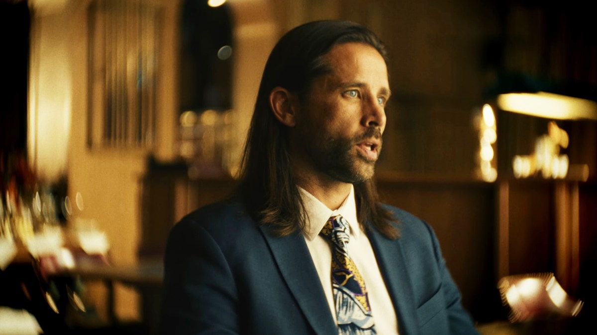 A close-up of Scott Dahlstrom sitting and wearing a dark blue suit with a colorful tie.