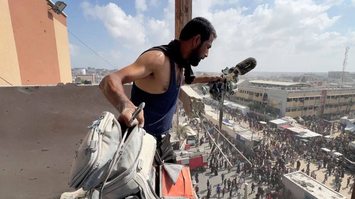 Man inspects damaged broadcast equipment at Nasser Hospital in Gaza after Israeli strike.