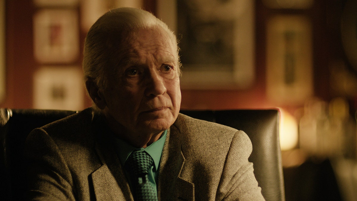 Marlin Hopkins wearing a beige blazer and a green shirt.