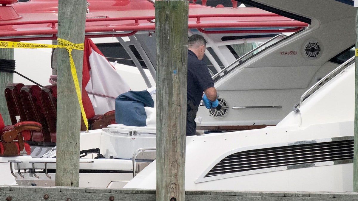 A law enforcement official, wearing disposable blue cleaning gloves, is seen investigating the yacht